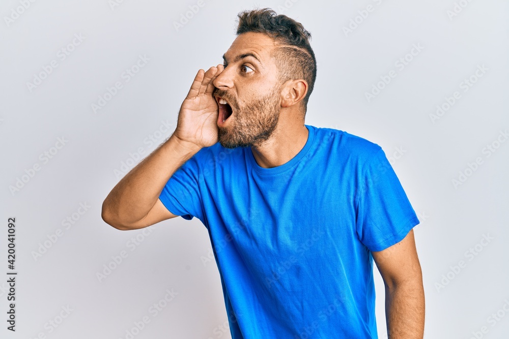 Handsome man with beard wearing casual clothes shouting and screaming loud to side with hand on mouth. communication concept. Handsome man with beard wearing casual clothes shouting and screaming loud to side with hand on mouth. communication concept.
