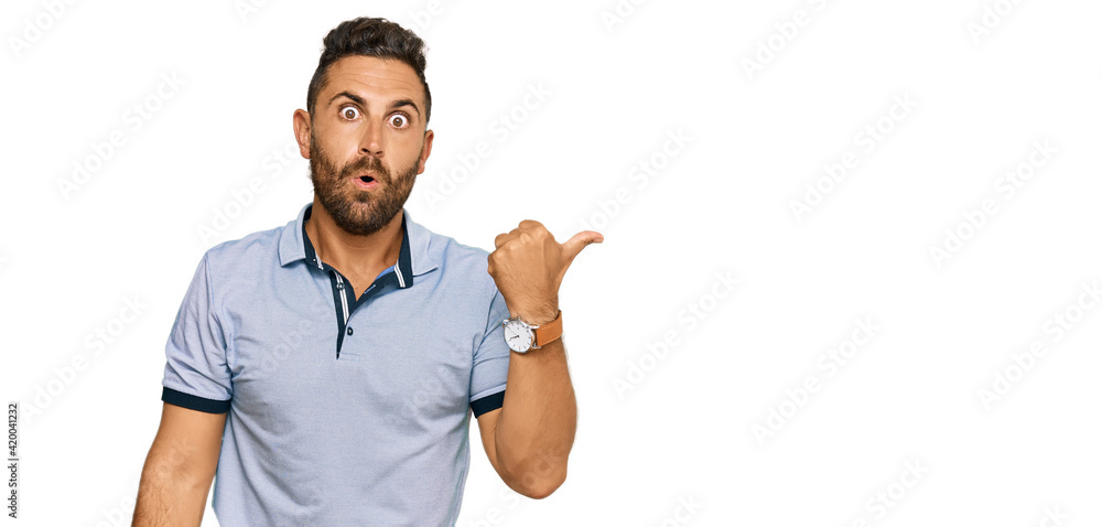 Handsome man with beard wearing casual clothes surprised pointing with hand finger to the side, open mouth amazed expression. Handsome man with beard wearing casual clothes surprised pointing with hand finger to the side, open mouth amazed expression.