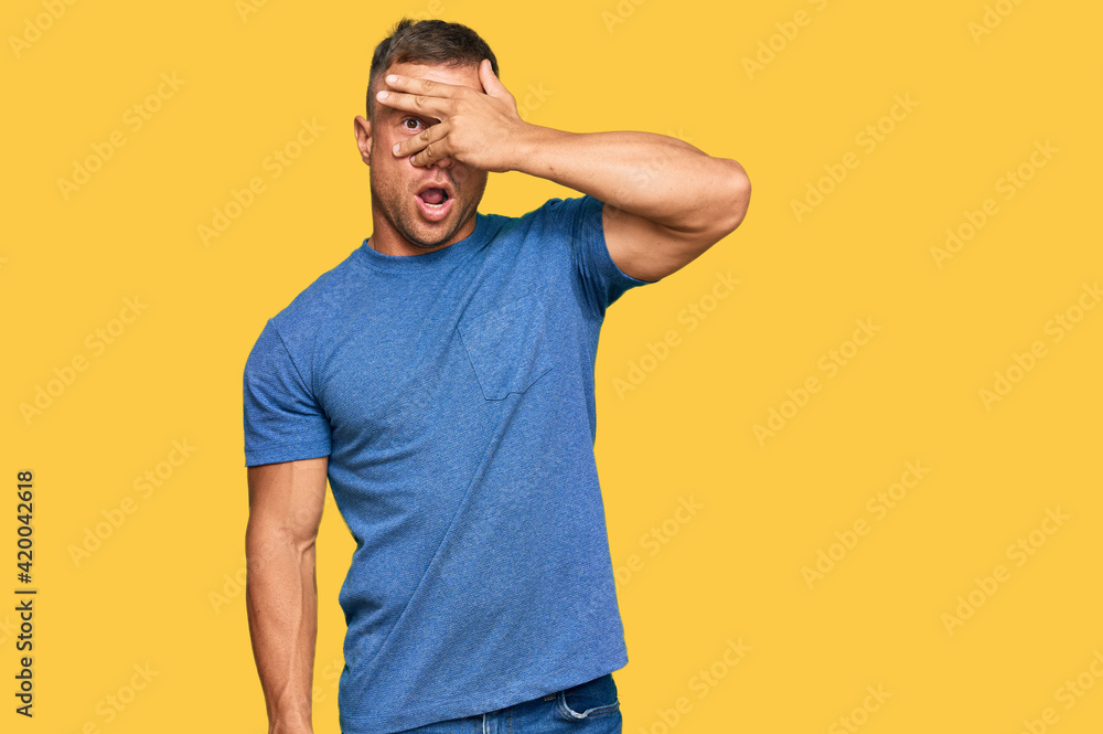 Handsome muscle man wearing casual clothes peeking in shock covering face and eyes with hand, looking through fingers with embarrassed expression. Handsome muscle man wearing casual clothes peeking in shock covering face and eyes with hand, looking through fingers with embarrassed expression.
