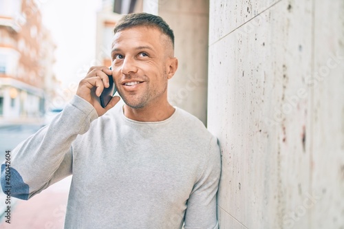 Young caucasian man smiling happy talking on the smartphone at the city.