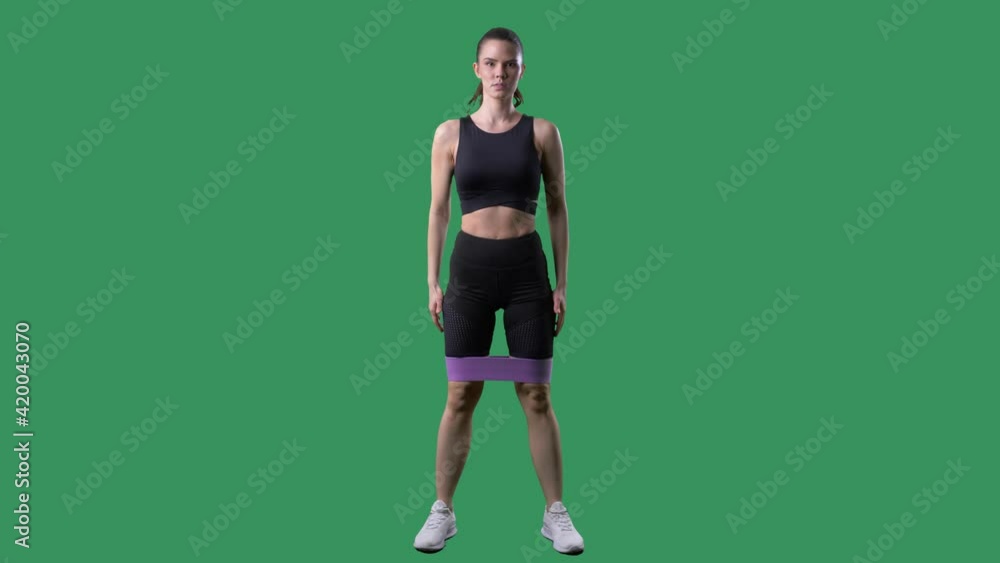 Fit woman doing squat exercise with resistance bands. Full body on green screen chroma background. Fit woman doing squat exercise with resistance bands. Full body on green screen chroma background.