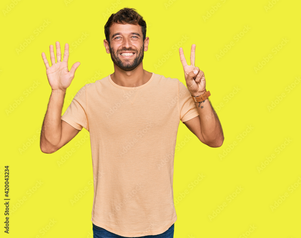 Handsome young man with beard wearing casual tshirt showing and pointing up with fingers number seven while smiling confident and happy. Handsome young man with beard wearing casual tshirt showing and pointing up with fingers number seven while smiling confident and happy.