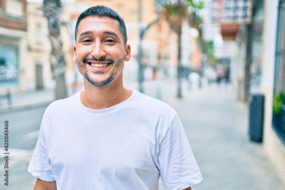 Young hispanic man smiling happy walking at street of city.