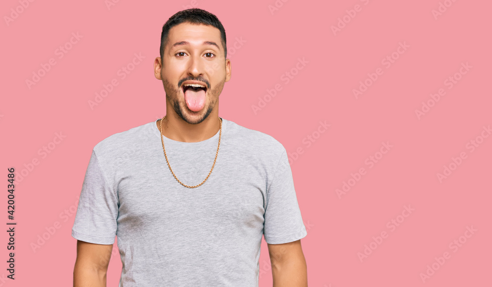 Handsome man with tattoos wearing 90s style sticking tongue out happy with funny expression. emotion concept. Handsome man with tattoos wearing 90s style sticking tongue out happy with funny expression. emotion concept.