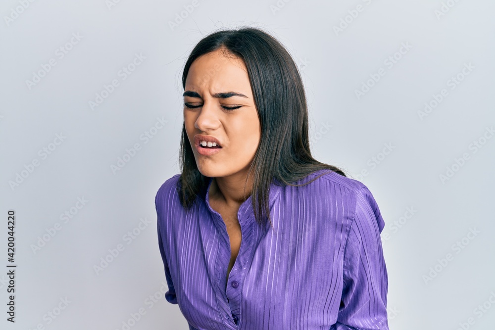 Young brunette woman wearing casual clothes with hand on stomach because nausea, painful disease feeling unwell. ache concept.