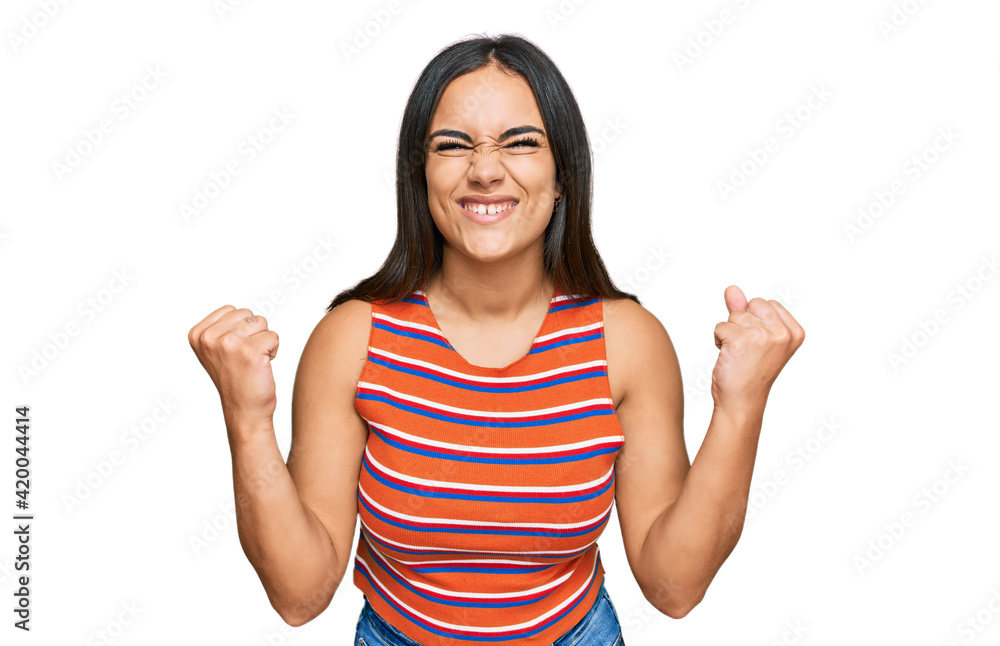 Young brunette woman wearing casual clothes celebrating surprised and amazed for success with arms raised and open eyes. winner concept. Young brunette woman wearing casual clothes celebrating surprised and amazed for success with arms raised and open eyes. winner concept.