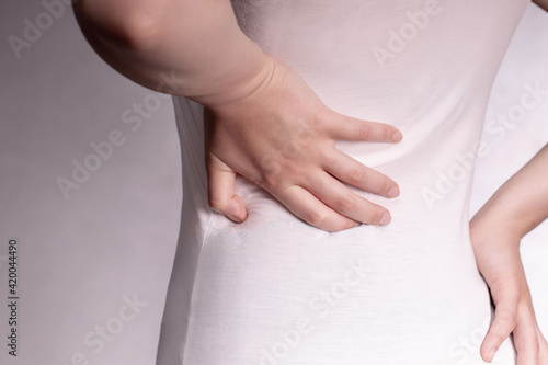 Woman with abdominal pain on gray background .Pain in the kidney.