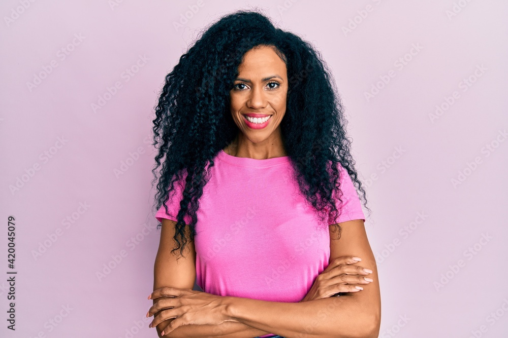 Middle age african american woman wearing casual clothes happy face smiling with crossed arms looking at the camera. positive person. Middle age african american woman wearing casual clothes happy face smiling with crossed arms looking at the camera. positive person.