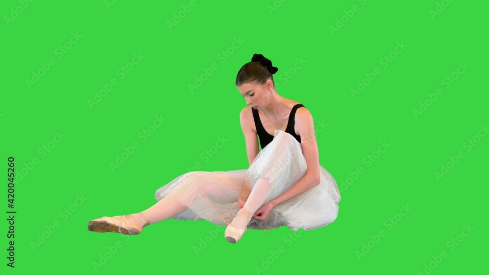 Ballerina laces up pointe with ballet ribbons while sitting on the floor on a Green Screen, Chroma Key. Ballerina laces up pointe with ballet ribbons while sitting on the floor on a Green Screen, Chroma Key.