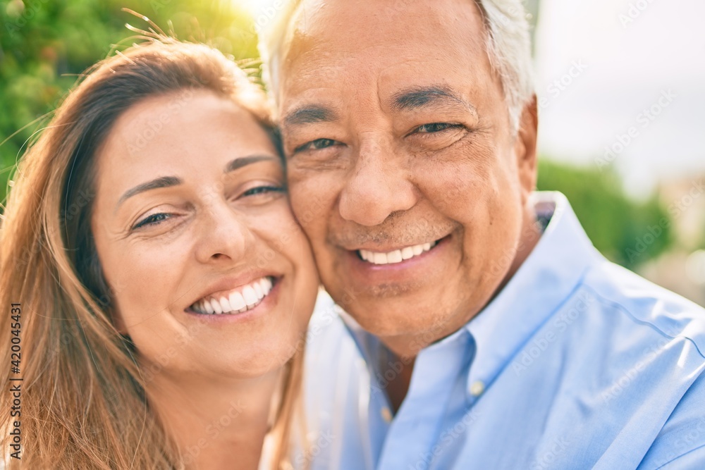 Middle age hispanic couple smiling happy hugging at the promenade.