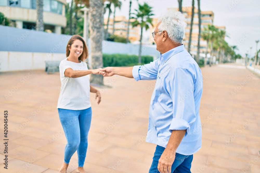 Middle age couple in love dancing at promenade happy and cheerful together
