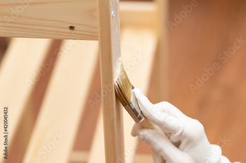 Painting wooden furniture for protection. Hand paints a rack with a brush