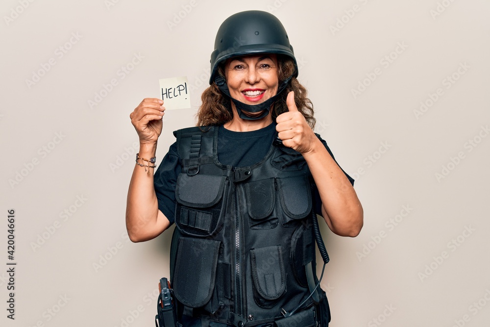 Middle age soldier woman wearing uniform and security helmet holding help reminder paper smiling happy and positive, thumb up doing excellent and approval sign Middle age soldier woman wearing uniform and security helmet holding help reminder paper smiling happy and positive, thumb up doing excellent and approval sign