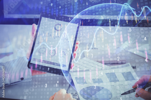 Double exposure of man's hands holding and using a digital device and forex graph drawing. Financial market concept.