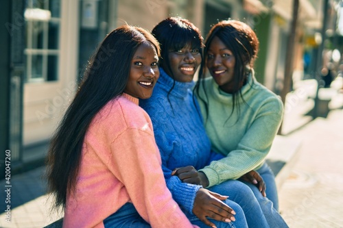 Three african american friends smiling happy hugging at the city. © Krakenimages.com