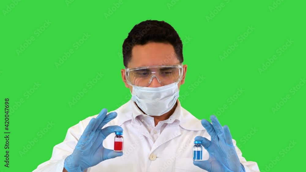 The doctor looking at the two new vaccines in ampoules and makes a choice showing the red one to camera on a Green Screen, Chroma Key. The doctor looking at the two new vaccines in ampoules and makes a choice showing the red one to camera on a Green Screen, Chroma Key.