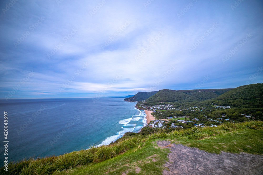 Ocean view from a hill. View of the bay with emerald green water and blue cloudy sky