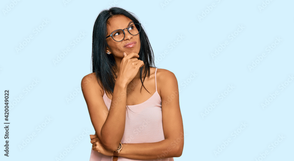 Fototapeta premium Young african american woman wearing casual clothes and glasses thinking worried about a question, concerned and nervous with hand on chin