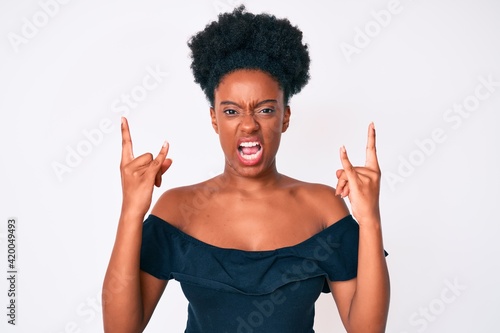 Young african american woman wearing casual clothes shouting with crazy expression doing rock symbol with hands up. music star. heavy concept.