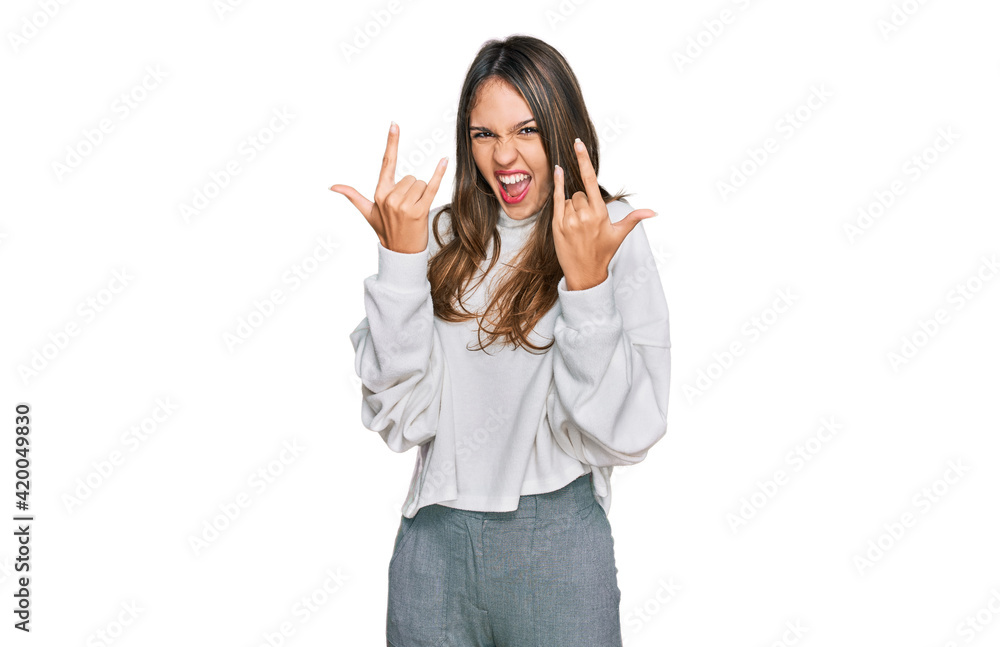 Young brunette woman wearing casual turtleneck sweater shouting with crazy expression doing rock symbol with hands up. music star. heavy concept. Young brunette woman wearing casual turtleneck sweater shouting with crazy expression doing rock symbol with hands up. music star. heavy concept.
