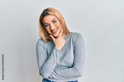 Young caucasian woman wearing casual clothes looking confident at the camera smiling with crossed arms and hand raised on chin. thinking positive.