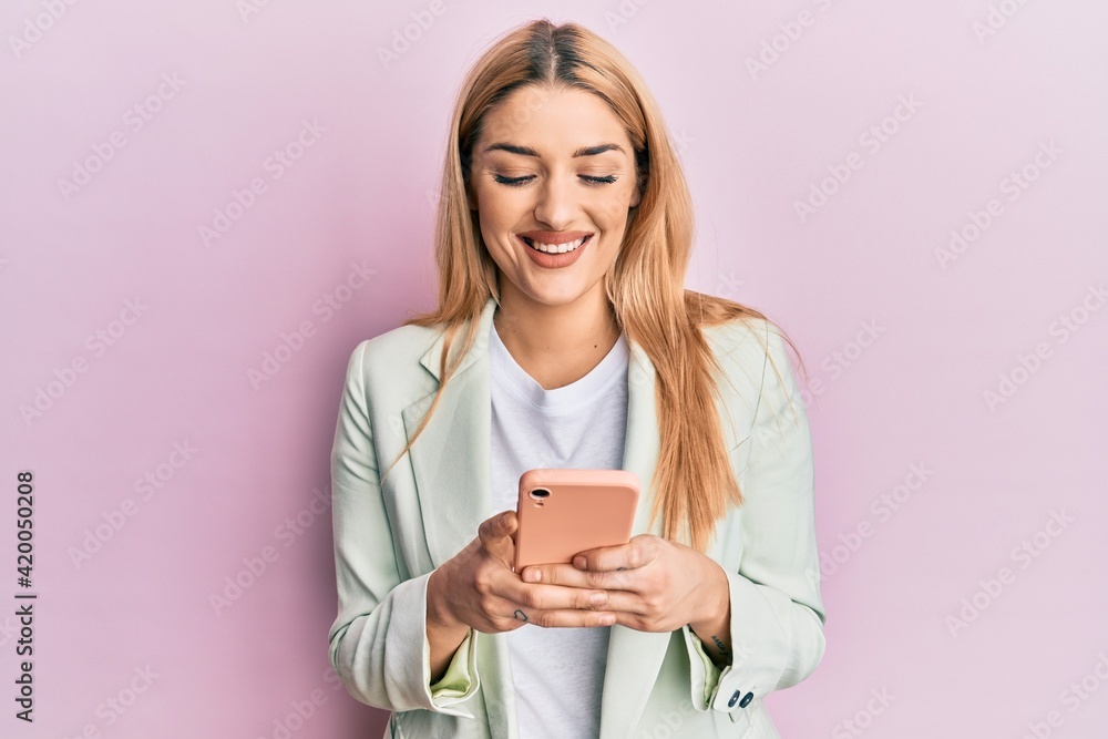 Young caucasian woman wearing business clothes using smartphone smiling with a happy and cool smile on face. showing teeth. Young caucasian woman wearing business clothes using smartphone smiling with a happy and cool smile on face. showing teeth.