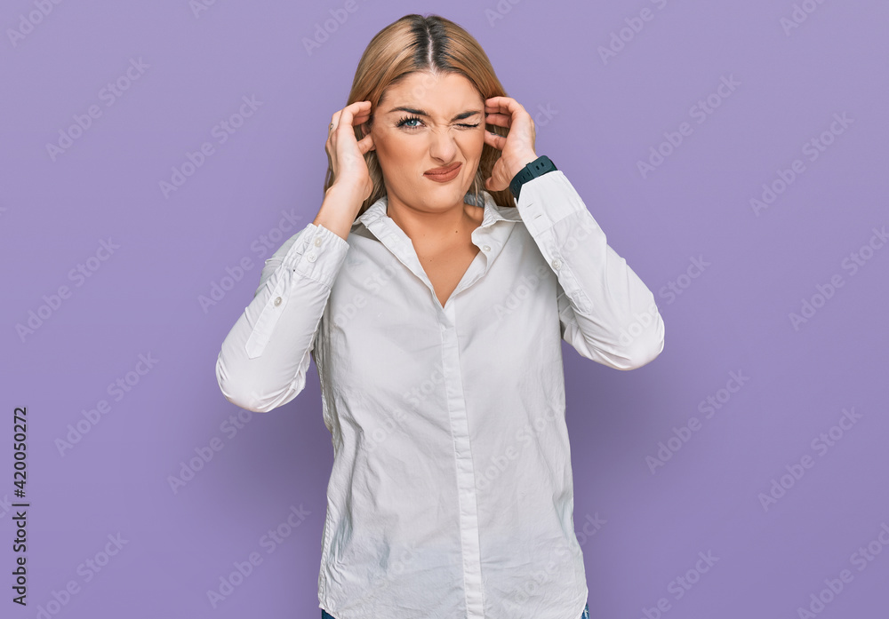 Young caucasian woman wearing casual clothes covering ears with fingers with annoyed expression for the noise of loud music. deaf concept. Young caucasian woman wearing casual clothes covering ears with fingers with annoyed expression for the noise of loud music. deaf concept.
