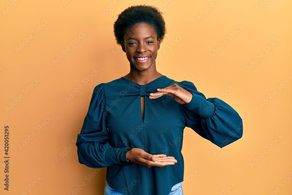 Young african american girl wearing casual clothes gesturing with hands showing big and large size sign, measure symbol. smiling looking at the camera. measuring concept. Young african american girl wearing casual clothes gesturing with hands showing big and large size sign, measure symbol. smiling looking at the camera. measuring concept.