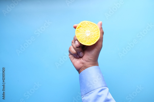 holding a slice of orange fruit on blue background 