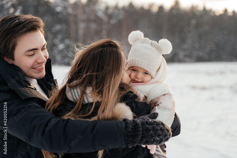 Young parernts holding small daughter in winter forest Young parernts holding small daughter in winter forest