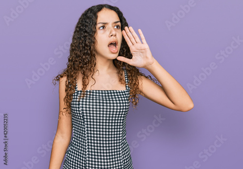 Teenager hispanic girl wearing casual clothes shouting and screaming loud to side with hand on mouth. communication concept.