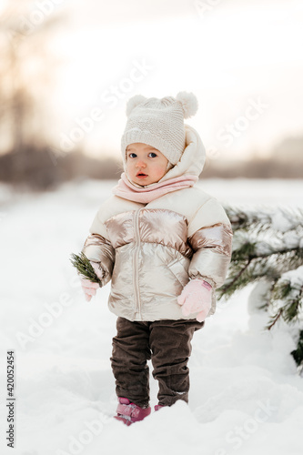 Small girl standing in winter forest at sunset  