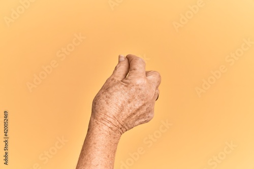 Senior caucasian hand over yellow isolated background holding blank space with thumb finger, business and advertising