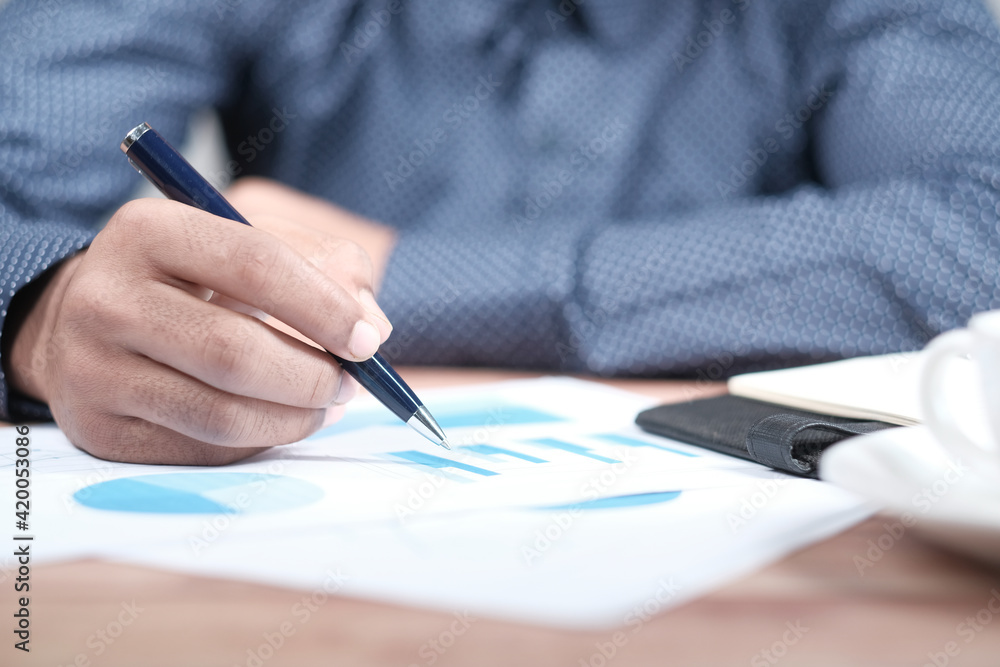 man hand with pen analyzing financial graph on table man hand with pen analyzing financial graph on table