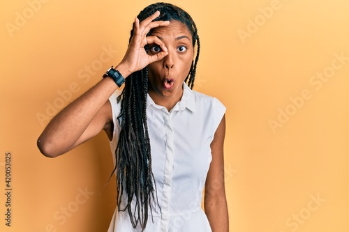 African american woman wearing casual clothes doing ok gesture shocked with surprised face, eye looking through fingers. unbelieving expression.