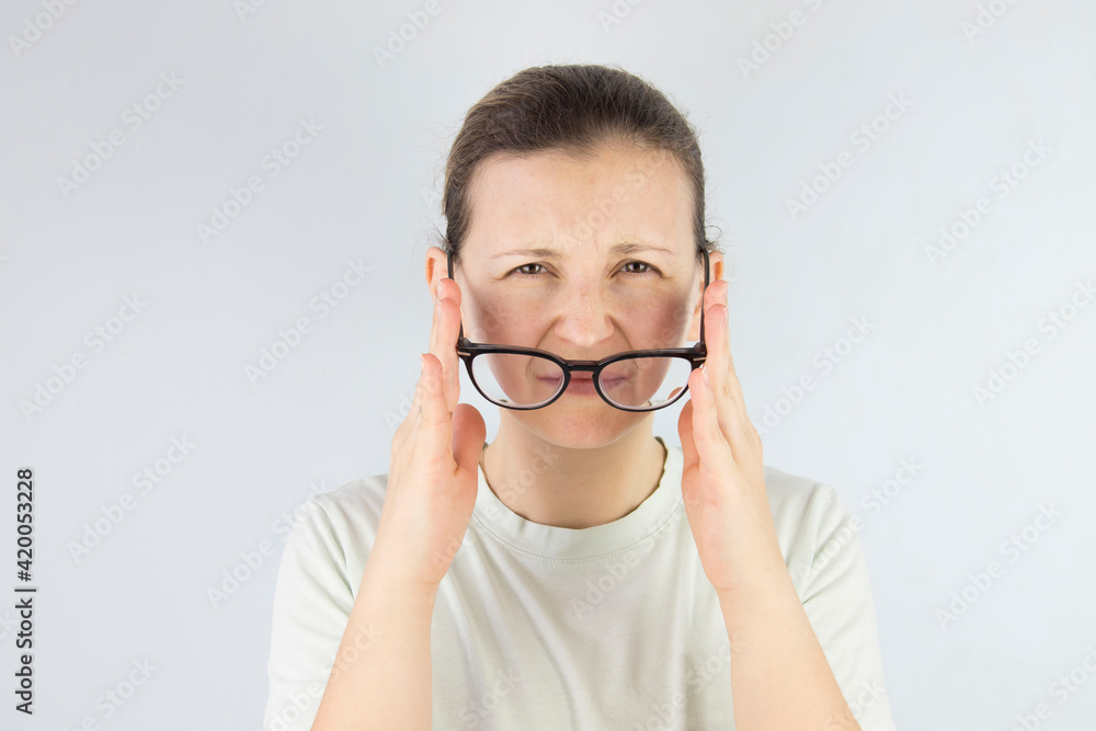 young woman rubs tired eyes from glasses, poor eyesight, vision problems. young woman rubs tired eyes from glasses, poor eyesight, vision problems.