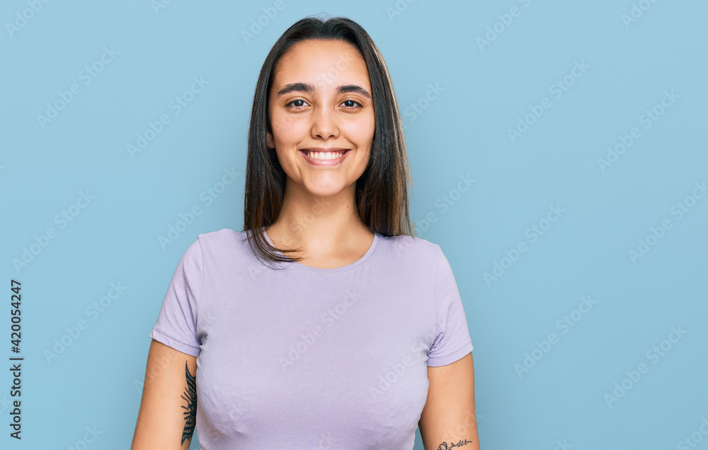 Obraz premium Young hispanic woman wearing casual clothes looking positive and happy standing and smiling with a confident smile showing teeth