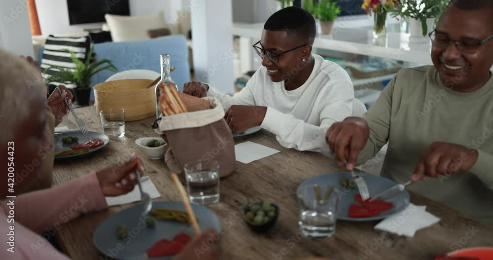 Happy african family eating lunch at home - Father, daughter, son and mother having fun together sitting at dinner table Happy african family eating lunch at home - Father, daughter, son and mother having fun together sitting at dinner table