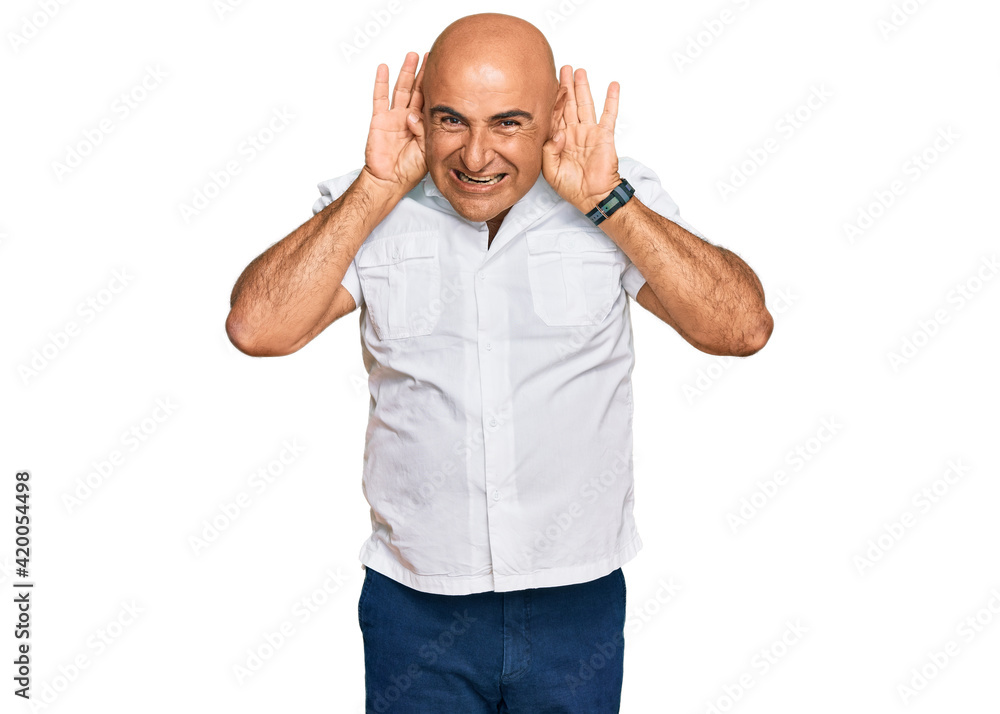 Mature middle east man with mustache wearing casual white shirt trying to hear both hands on ear gesture, curious for gossip. hearing problem, deaf Mature middle east man with mustache wearing casual white shirt trying to hear both hands on ear gesture, curious for gossip. hearing problem, deaf