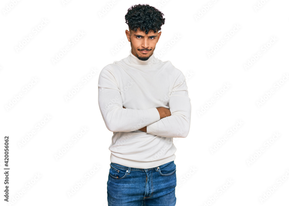 Young arab man wearing casual winter sweater skeptic and nervous, disapproving expression on face with crossed arms. negative person. Young arab man wearing casual winter sweater skeptic and nervous, disapproving expression on face with crossed arms. negative person.