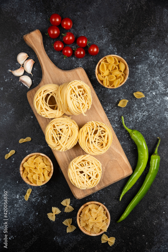 Noodle rolls with green chilies, cherry tomatoes and garlic on a wooden board Noodle rolls with green chilies, cherry tomatoes and garlic on a wooden board
