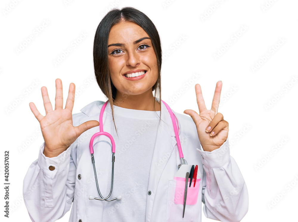Beautiful hispanic woman wearing doctor uniform and stethoscope showing and pointing up with fingers number eight while smiling confident and happy. Beautiful hispanic woman wearing doctor uniform and stethoscope showing and pointing up with fingers number eight while smiling confident and happy.