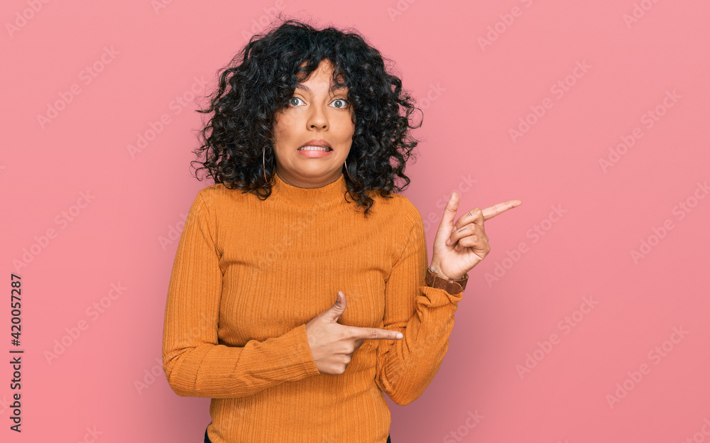 Young hispanic woman wearing casual clothes pointing aside worried and nervous with both hands, concerned and surprised expression Young hispanic woman wearing casual clothes pointing aside worried and nervous with both hands, concerned and surprised expression