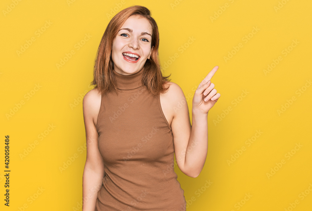 Young caucasian woman wearing casual clothes with a big smile on face, pointing with hand and finger to the side looking at the camera. Young caucasian woman wearing casual clothes with a big smile on face, pointing with hand and finger to the side looking at the camera.