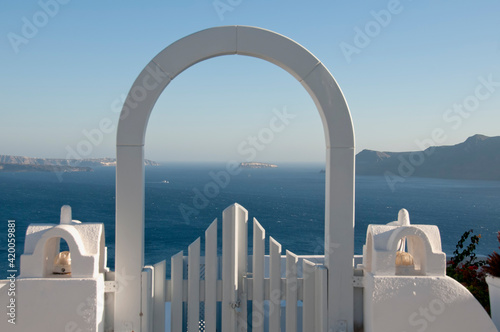 Architectural arched door in a terrace with panoramic views on the island of Santorini, Greece. In the background the caldera of the volcano and the Aegean Sea. Europe