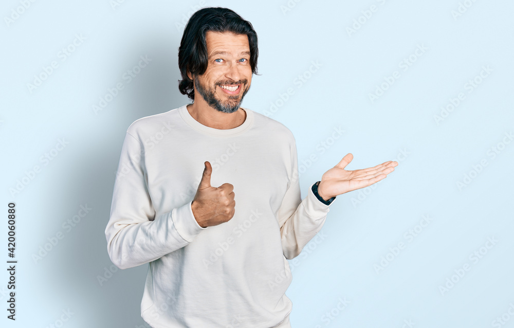 Middle age caucasian man wearing casual clothes showing palm hand and doing ok gesture with thumbs up, smiling happy and cheerful Middle age caucasian man wearing casual clothes showing palm hand and doing ok gesture with thumbs up, smiling happy and cheerful