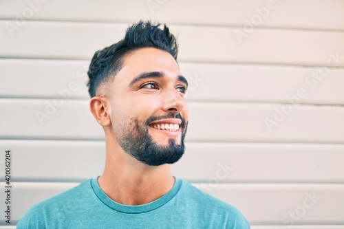 Young arab man smiling happy leaning on the wall at the city.