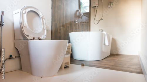 Spacious bathroom in white tones with heated floors, freestanding tub, walk-in shower and sink vanity. modern Luxury bathroom interior with hanging toilet, sink, bath, faucet, mirror, shower.