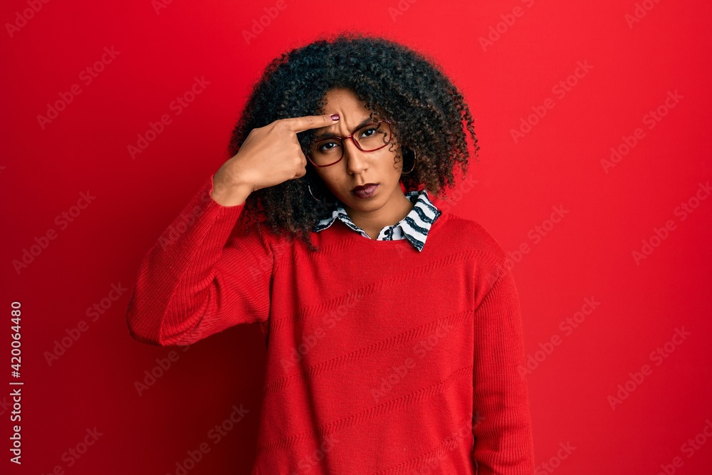 Beautiful african american woman with afro hair wearing sweater and glasses pointing unhappy to pimple on forehead, ugly infection of blackhead. acne and skin problem
