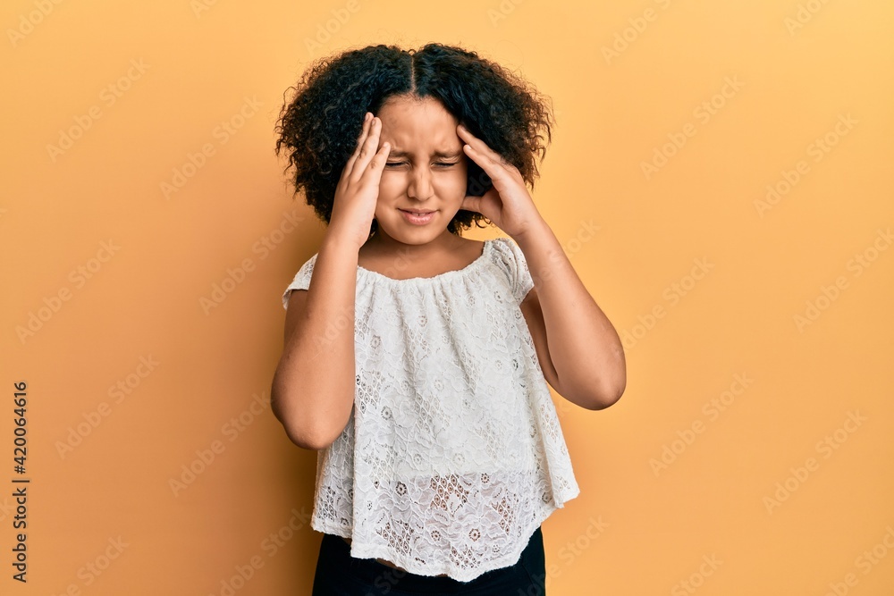 Young little girl with afro hair wearing casual clothes with hand on head for pain in head because stress. suffering migraine. Young little girl with afro hair wearing casual clothes with hand on head for pain in head because stress. suffering migraine.